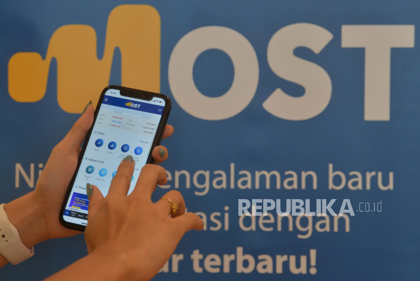 Model membuka aplikasi digital MOST (Mandiri Online Securities Trading) dengan tampilan yang baru di Jakarta, Rabu (30/11/2022). Mandiri Sekuritas optimistis IHSG masih memiliki energi untuk rebound ke level 7.510 pada tahun ini.