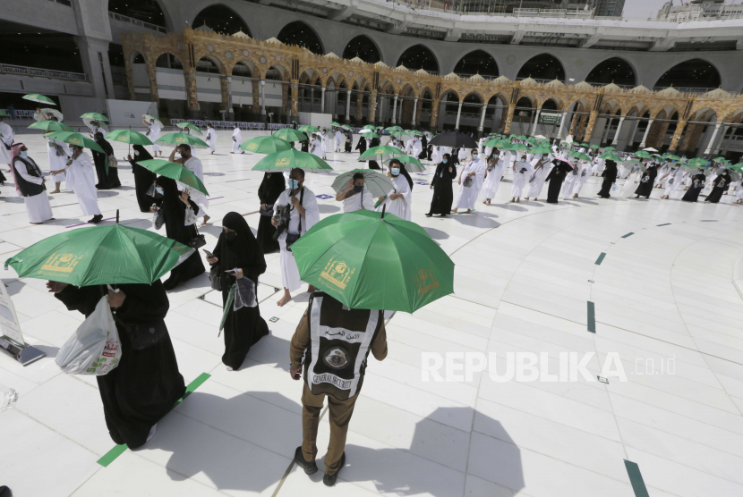 Seorang polisi Saudi, tengah, mengawasi peziarah saat mengelilingi Ka