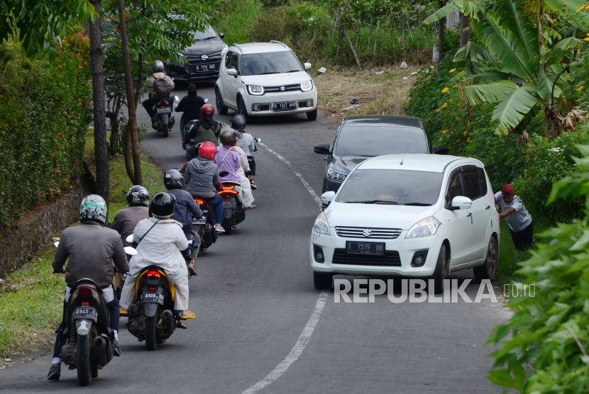 Warga membantu mendorong kendaraan yang tidak kuat menanjak di jalur alternatif menuju Lembang, di Jalan Punclut, Kecamatan Lembang, Kabupaten Bandung Barat, Jumat(30/10). Banyaknya kendaraan yang berhenti ditanjakan menjadi salah satu penyebab kemacetan di jalur punclut.