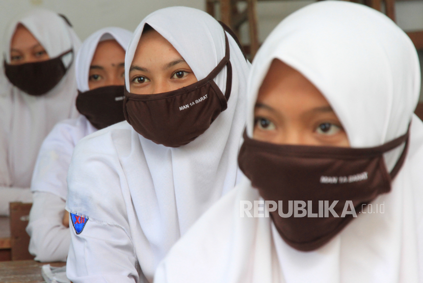 Sejumlah siswi dengan menggunakan masker mengikuti proses belajar mengajar.