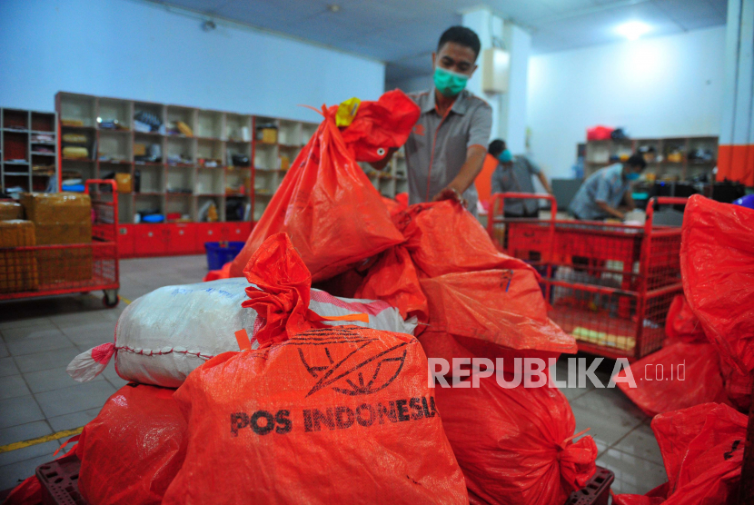 Karyawan dengan menggunakan masker menyortir barang paket kiriman di Kantor PT Pos Indonesia .
