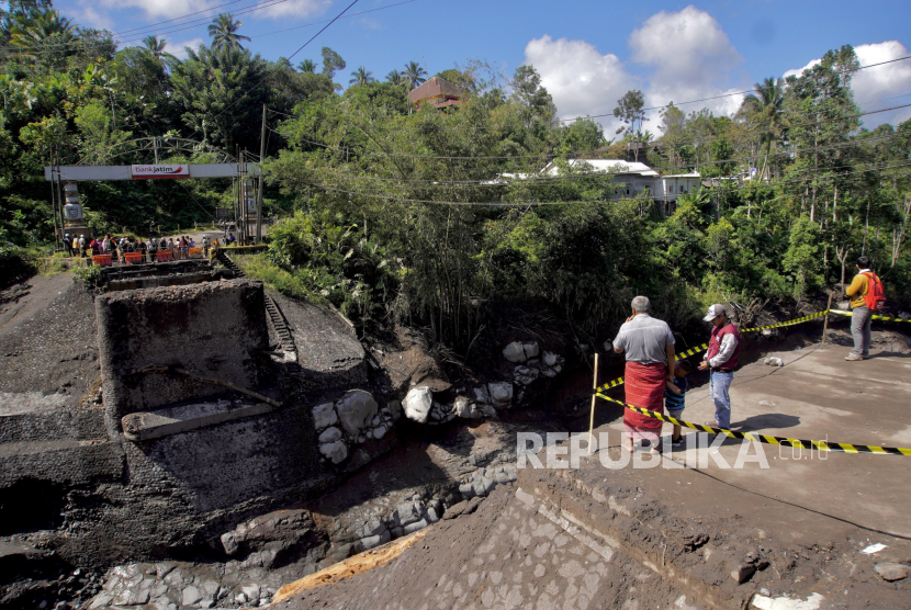 Warga mengamati kondisi Jembatan Kali Glidik di Pronojiwo, Lumajang, Jawa Timur, Senin (10/7/2023). Jembatan penghubung Malang-Lumajang tersebut putus akibat diterjang lahar hujan Gunung Semeru pada Jumat (7/7).  