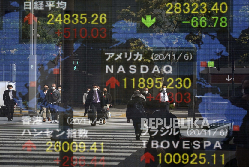  Para pejalan kaki tercermin dalam papan indikator pasar saham di Tokyo, Jepang, 09 November 2020. Saham Asia melonjak pada Selasa (29/12), dengan saham Jepang mencapai tertinggi 29 tahun. 