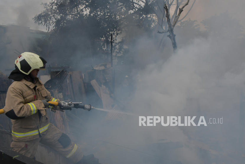 Sejumlah petugas memadamkan api yang membakar rumah padat penduduk di Jalan Kebayoran Lama, Jakarta Selatan, Ahad (30/10/2022).