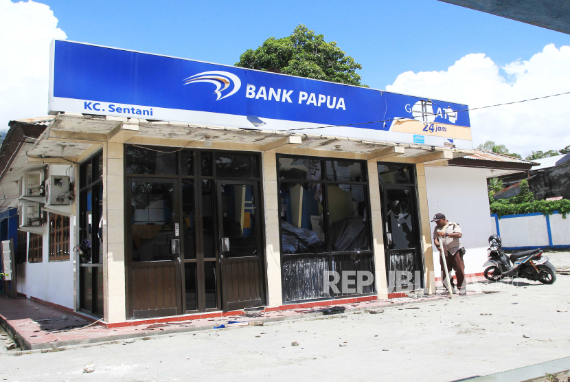 Seorang petugas keamanan melihat kondisi kaca kantor yang rusak akibat di lempar oleh massa di Bank BPD Kantor Cabang Sentani, Kabupaten Jayapura, Papua, Kamis (28/12/2023). 