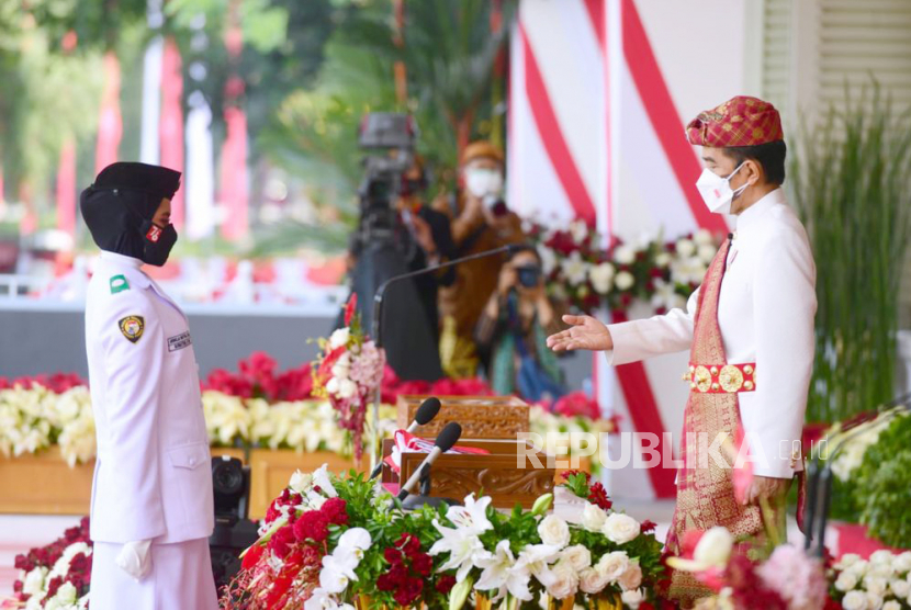 Presiden Joko Widodo (kanan) mempersilahkan anggota Paskibraka pembawa baki asal Sumatra Utara Ardelia Muthia Zahwa untuk mengambil bendera merah putih untuk dikibarkan saat Upacara Peringatan Detik-Detik Proklamasi 1945 di Istana Merdeka, Jakarta, Selasa (17/8/2021). Peringatan HUT Kemerdekaan ke-76 Republik Indonesia ini mengangkat tema Indonesia Tangguh Indonesia Tumbuh. 
