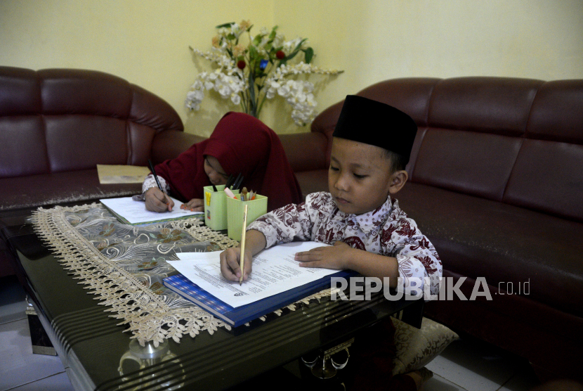 Dua siswa Madrasah Ibtidaiyyah Madani Alauddin mengerjakan soal ujian semester genap di rumahnya di Kabupaten Gowa, Sulawesi Selatan, Selasa (2/6/2020). Pelaksanaan ujian semester genap secara manual (offline) di rumah tersebut sebagai langkah pihak sekolah dalam menerapkan pembatasan sosial guna pencegahan  penyebaran COVID-19 di lingkungan sekolah