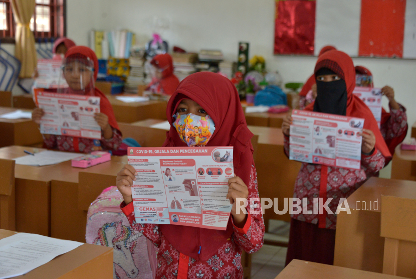 Sejumlah murid memperlihatkan poster sosialisasi pencegahan COVID-19 sebelum pembagian masker di salah satu Sekolah Dasar Negeri, Desa Garut, Kecamatan Darul Imara, Kabupaten Aceh Besar, Aceh, Selasa (2/12/2020). Pemerintah Aceh meluncurkan Gerakan Masker Sekolah (Gemas) dengan menyasar sebanyak 1,08 juta pelajar dari 6.783 sekolah di Aceh  dengan melibatkan 117.712 guru untuk memastikan penerapan protokol kesehatan dengan benar di sekolah guna mencegah penyebaran COVID-19 menjelang pemberlakukan belajar tatap muka secara normal. 