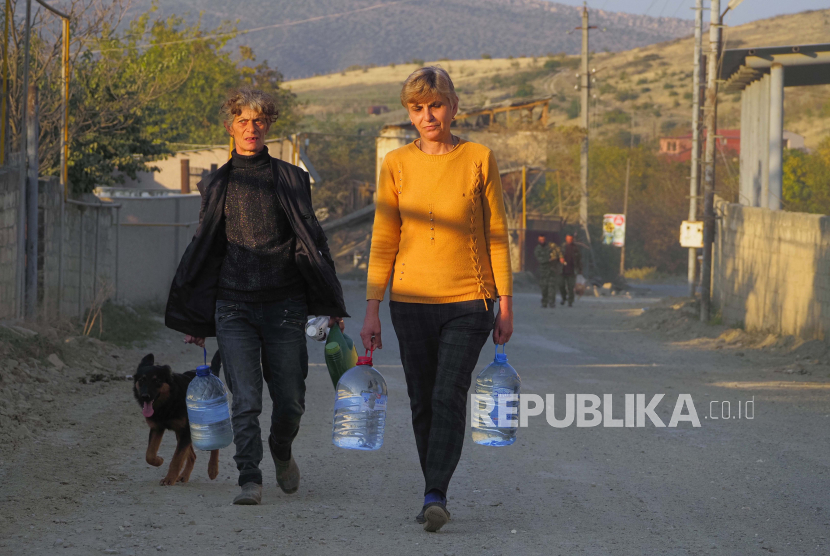 Penduduk setempat membawa air selama konflik militer di kota garis depan Martakert, wilayah separatis Nagorno-Karabakh, Senin, 19 Oktober 2020. Penembakan baru telah dilaporkan dalam pertempuran antara Armenia dan Azerbaijan, melanggar gencatan senjata akhir pekan. dalam konflik atas wilayah separatis Nagorno-Karabakh. Pertempuran berkecamuk selama lebih dari tiga minggu.