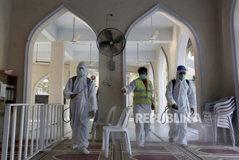 Relawan menyemprotkan disinfektan di sebuah masjid dalam upaya menahan wabah virus corona.