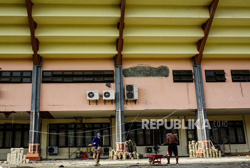 Dua pekerja menyelesaikan renovasi lahan parkir di Gedung Olahraga (GOR) Waringin, Kota Jayapura, Papua, Kamis (8/7/2021). Jelang PON, kepolisian terus tingkatkan deteksi gangguan keamanan di Papua.