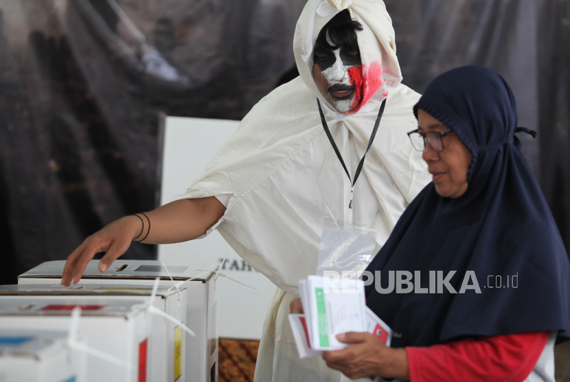 Petugas KPPS mengenakan kostum hantu membatu warga memasukkan suart suara Pemilu 2024 usai mencoblos di Tempat Pemungutan Suara (TPS) 23 di Rangkah, Surabaya, Jawa Timur, Rabu (14/2/2024). Penggunaan kostum bertema hantu tersebut bertujuan untuk menarik warga agar menggunakan hak pilihnya dalam Pemilu 2024. 