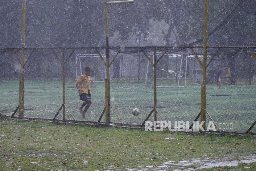 Sejumlah anak bermain bola saat hujan di Taman Persib di Jalan Supratman, Kota Bandung, Jumat (20/1/2023). Cuaca Hari Ini: Hujan Diprakirakan Turun di Sebagian Wilayah Indonesia