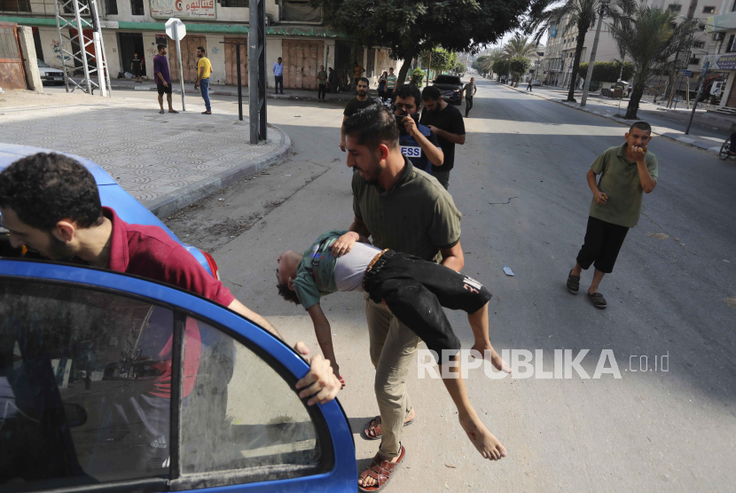 Seorang pria menggendong anak korban bom Israel di Kota Gaza