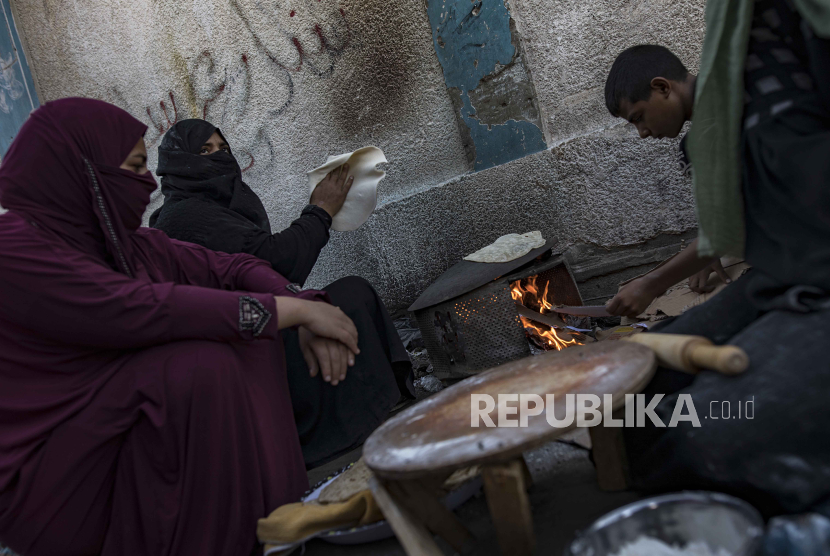 Pengungsi Palestina menyiapkan roti menggunakan kayu bakar akibat kekurangan gas di kamp pengungsi Khan Yunis, Jalur Gaza selatan, 17 November 2023. Lebih dari 11.000 warga Palestina dan setidaknya 1.200 warga Israel tewas, menurut Pasukan Pertahanan Israel (IDF) dan Israel.
