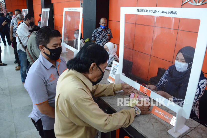 Petugas mendampingi pengunjung saat melakukan transaksi produk Kopnuspos di Kantor Pos, Jalan Asia Afrika, Kota Bandung, Jumat (5/2/2021). 