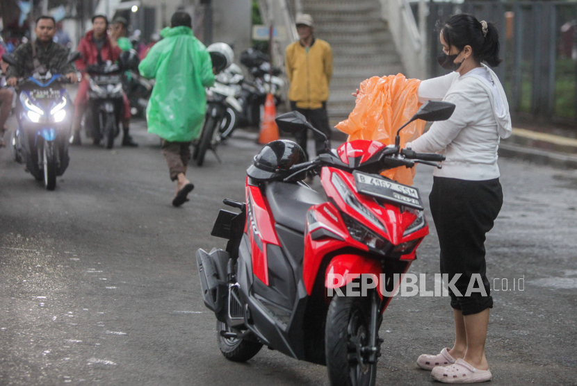 Pengendara motor memakai jas hujan saat hujan mengguyur (ilustrasi).