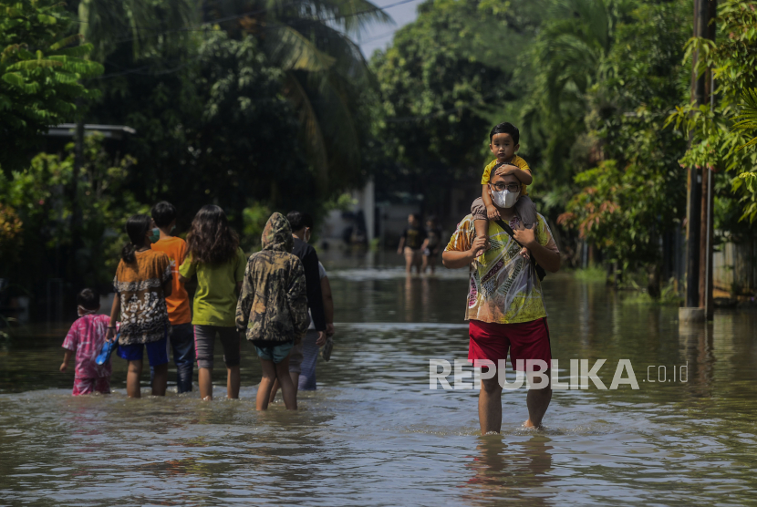 Seorang warga menggendong anaknya saat terjadi banjir di Perumahan Nerada Estate, Ciputat, Tangerang Selatan.