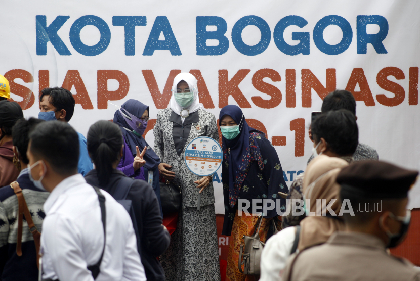 Warga melintas di depan spanduk sosialisasi tentang vaksinasi COVID-19 di Puskesmas Tanah Sareal, Kota Bogor, Jawa Barat, Kamis (14/1/2021). Sosialisasi tersebut bertujuan agar masyarakat umum tidak takut melakukan vaksinasi COVID-19. 