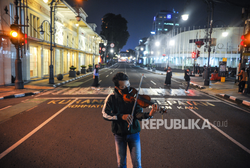 Seorang pengamen memainkan biolanya saat penutupan Jalan Asia Afrika di Bandung. (Ilustrasi)