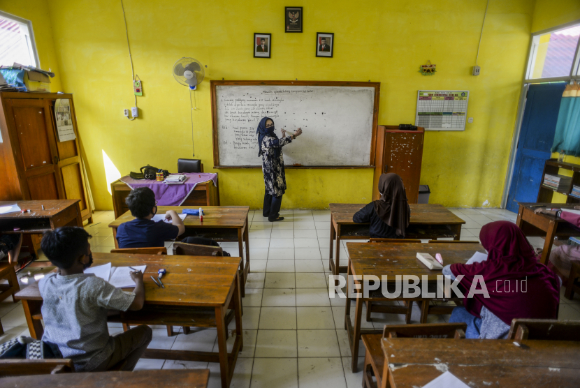 Seorang guru memberikan penjelasan kepada anak-anak saat uji coba pembelajaran tatap muka (PTM) di SDN Cihideung Ilir 5, Ciampea, Kabupaten Bogor, Jawa Barat, Rabu (25/8). 
