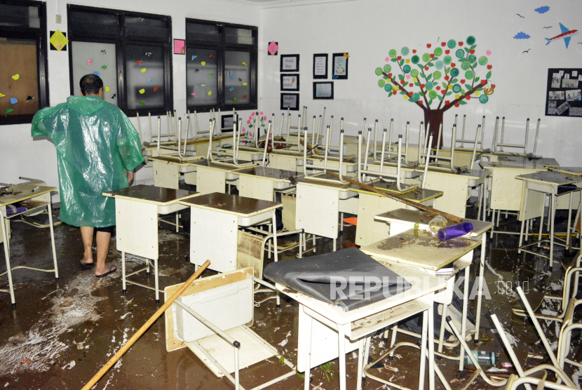 Seorang petugas mengamati ruang kelas saat banjir di MTsN 19 Jakarta, Pondok Labu, Jakarta, Kamis (6/10/2022). Sebanyak tiga siswa meninggal tertimpa tembok yang roboh akibat terjangan banjir yang menggenangi sekolah tersebut. 
