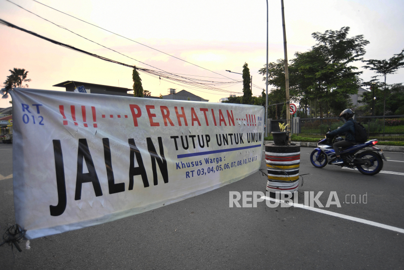 Pengendara sepeda bermotor melintasi spanduk penutupan jalan di kawasan Pondok Pinang, Jakarta, Rabu (1/4/2020). Penutupan jalan di kawasan Pondok Pinang, Kecamatan Kebayoran Lama tersebut merupakan inisiatif warga untuk mencegah penyebaran virus corona (COVID-19) di sekitar tempat tinggal mereka