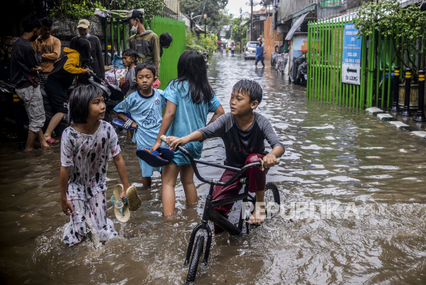 Anak-anak bermain saat terjadi banjir di Jalan Bungur Besar Raya, Kemayoran, Jakarta, Selasa (18/1/2022). Banjir tersebut terjadi karena buruknya drainase di jalan tersebut serta tingginya intensitas hujan. Republika/Putra M. Akbar