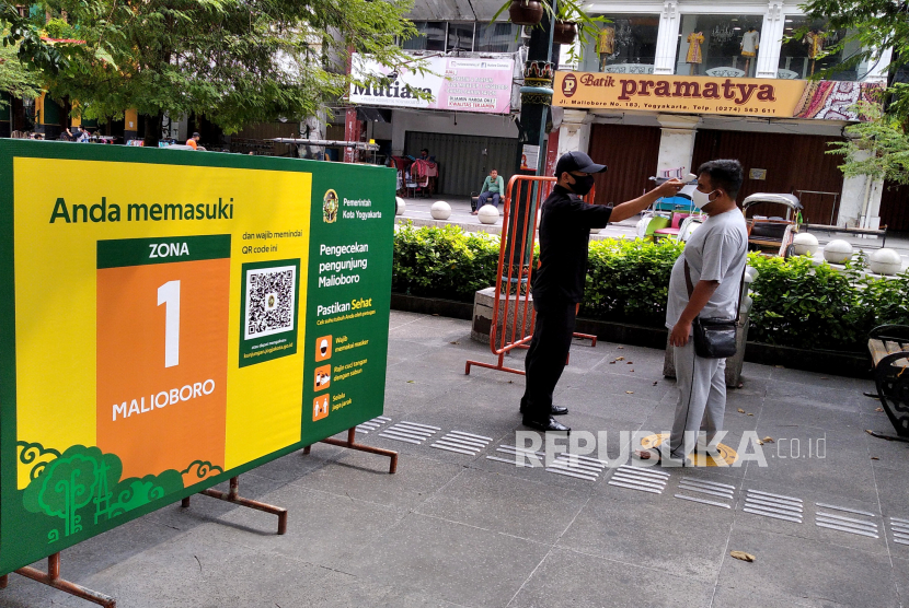 Petugas megukur suhu tubuh pengunjung sebelum memasuki kawasan wisata Malioboro, Yogyakarta, Ahad (19/7). Protokol kesehatan Covid-19 menjadi panduan wajib di tempat wisata Yogyakarta. wajib menggunakan masker, mencuci tangan, dan pengukuran suhu tubuh selalu dilakukan oleh petugas. Ini dilakukan untuk menekan penyebaran virus Covid-19. Dan Yogyakarta masih belum terbebas dari penambahan pasien Covid-19.