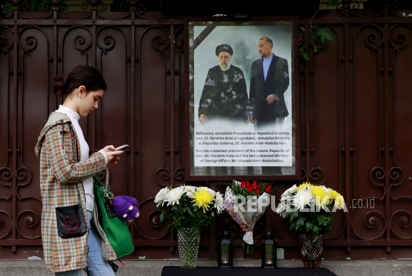 Seorang wanita muda berjalan melewati tugu peringatan darurat yang dipasang di luar kedutaan Iran, menyusul kematian Presiden Iran Ebrahim Raisi dan Menteri Luar Negeri Amir-Abdollahian, di Bucharest, Rumania, 20 Mei 2024. 