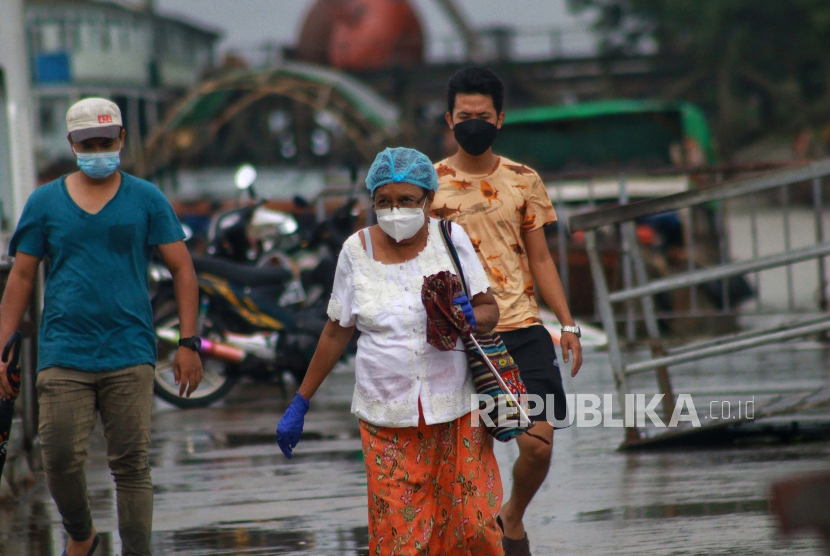 Orang-orang memakai masker saat mereka berjalan di luar dermaga Dala di Yangon, Myanmar Selasa, 27 Juli 2021.