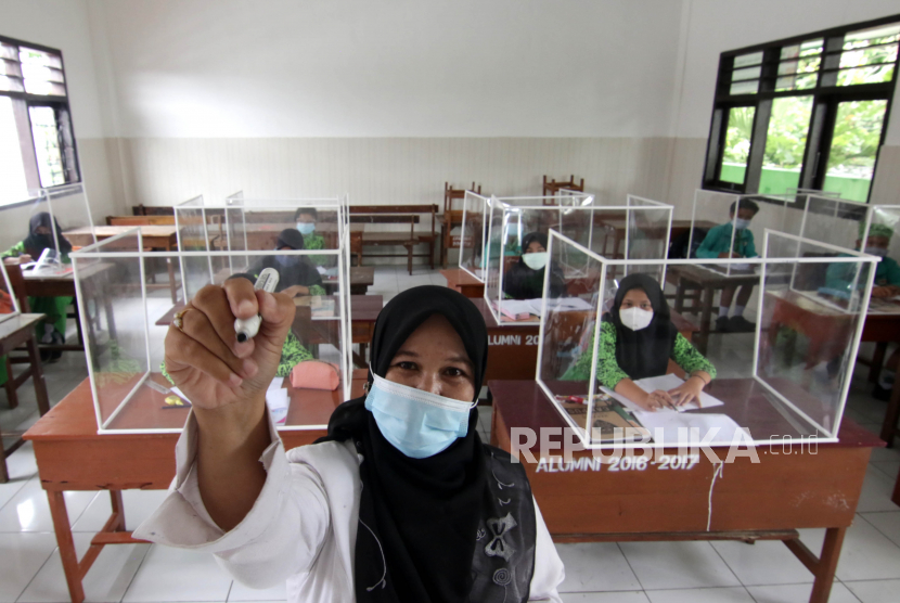 Guru mengajar tatap muka di kelas yang dilengkapi dengan bilik plastik di SDN 1 Lateng, Banyuwangi, Jawa Timur, Rabu (24/2/2021). Sebanyak 74 persen atau 984 SD di Banyuwangi sudah melakukan pembelajaran tatap muka dengan  pembatasan 30 persen dari total murid sedangkan sisanya masih mengikuti pembelajaran secara daring. 