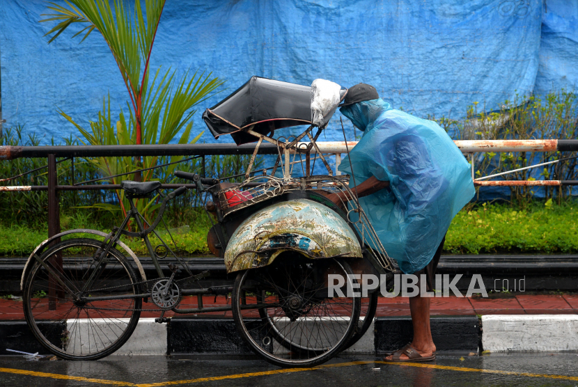 Tukang becak menggunakan jas hujan saat hujan di kawasan Ngabean, Yogyakarta. Badan Meteorologi Klimatologi dan Geofisika (BMKG) memperkirakan bahwa Jogja dilanda cuaca ekstrem. Kondisi tersebut membuat potensi curah hujan dengan intensitas sedang hingga lebat serta petir dan angin kencang.
