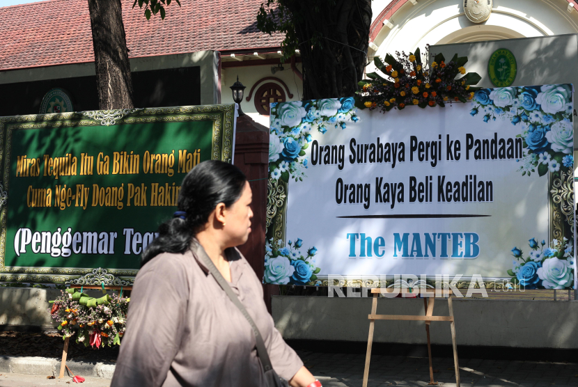 Warga berjalan di dekat karangan bunga yang terpajang di depan Gedung Pengadilan Negeri Surabaya, Jalan Arjuno, Surabaya, Jawa Timur, Senin (29/7/2024). Sekitar 16 karangan bunga dari berbagai kelompok masyarakat itu bernada kekecewaan terhadap keputusan majelis hakim yang memutus bebas Gregorius Ronald Tannur dari dakwaan terkait kasus dugaan penganiayaan yang berakibat kekasihnya bernama Dini Sera Afrianti meninggal dunia. 