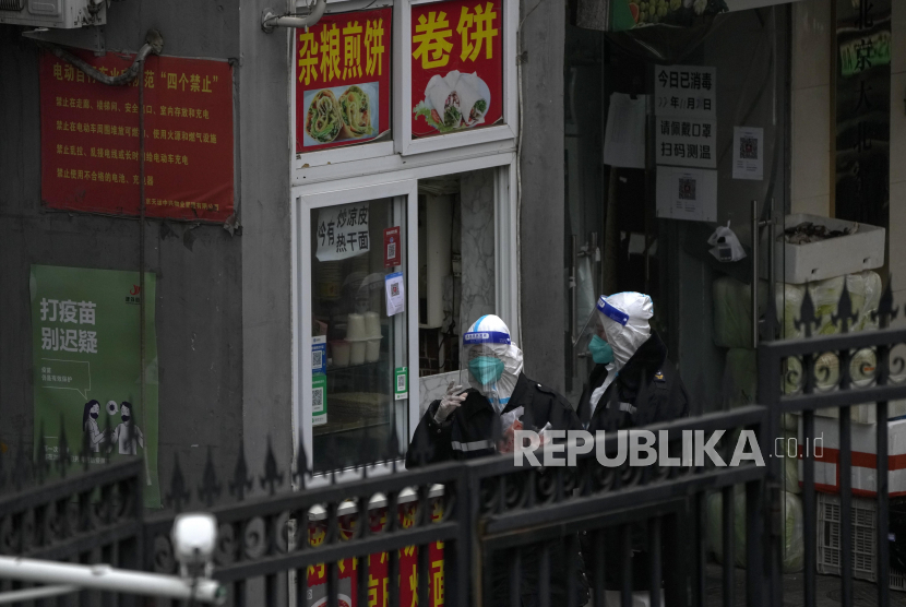 Workers in protective suits buy their breakfast from a store inside a locked down neighborhood as part of COVID-19 controls in Beijing, Thursday, Nov. 24, 2022. China is expanding lockdowns, including in a central city where factory workers clashed this week with police, as its number of COVID-19 cases hit a daily record. (AP Photo/Andy Wong)