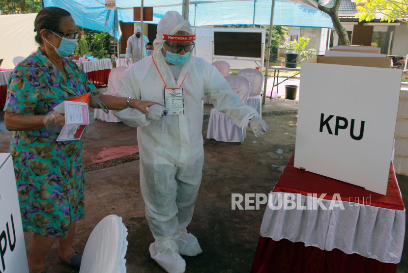 Petugas Kelompok Penyelenggara Pemungutan Suara (KPPS) berpakaian hazmat membantu pemilih menggunakan hak pilihnya di TPS 46 Paku Jaya, Serpong Utara, Tangerang Selatan, Banten, Rabu (9/12/2020). Penggunaan alat pelindung diri (APD) lengkap tersebut untuk meyakinkan masyarakat menggunakan hak pilihnya pada Pilkada Tangerang Selatan 2020 meski di tengah pandemi Covid-19. 