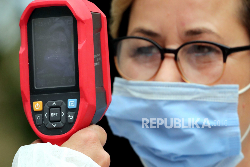  Seorang anggota staf medis mengukur suhu tubuh wanita saat orang-orang menjalani tes virus corona, di sebuah rumah sakit di Sarajevo, Bosnia dan Herzegovina, 10 September 2020. Negara-negara di seluruh dunia sedang mengambil langkah-langkah yang ditingkatkan untuk membendung penyebaran virus corona SARS-CoV-2 yang mana menyebabkan penyakit Covid-19.