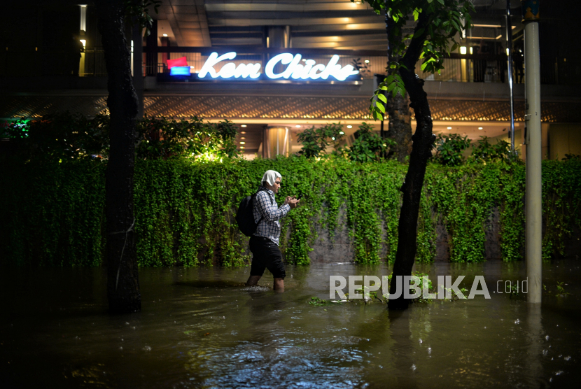 Warga berjalan menerobos banjir di Jalan Kemang Raya, Jakarta Selatan, Selasa (5/10/2022) malam WIB.