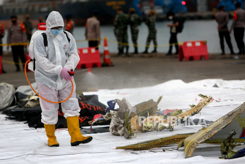[Ilustrasi] Petugas medis menyemprotkan desinfektan ke puing-puing pesawat Sriwijaya Air SJ-182 yang ditemukan di perairan Jakarta di Pelabuhan Tanjung Priok di Jakarta, Indonesia, Ahad (10/1).