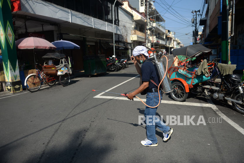 Relawan menyemprotkan desinfektan di jalan. 