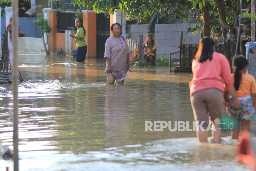 Warga melintasi banjir di desa Babadan, Kecamatan Sindang, Indramayu, Jawa Barat, Jumat (26/3/2021). Banjir akibat luapan sungai Cimanuk itu merendam puluhan rumah di dua desa yang berada di sekitar sungai tersebut.