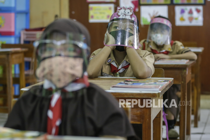  Siswa yang memakai pelindung wajah menghadiri kelas saat mereka mengikuti uji coba pembukaan kembali sekolah di Jakarta, Indonesia, 07 April 2021. 