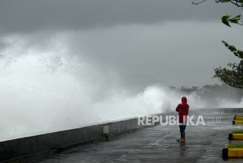 Seorang pria mengamati gelombang tinggi di Manado, Sulawesi Utara, Selasa (14/2/2023). 