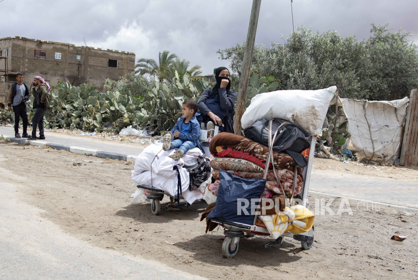 Seorang wanita dan anak-anak Palestina membawa barang-barang mereka di jalan, setelah perintah evakuasi dikeluarkan oleh tentara Israel, di Rafah, Jalur Gaza selatan, 6 Mei 2024.