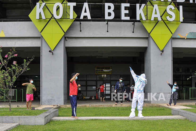 Petugas medis (kedua kanan) menggunakan Alat Pelindung Diri (APD) bersama pasien Covid-19 yang berstatus OTG (Orang Tanpa Gejala) saat kegiatan senam pagi di Stadion Patriot Chandrabhaga, Bekasi, Jawa Barat, Rabu (16/12/2020). Kegiatan senam tersebut rutin dilakukan setiap pagi hari untuk meningkatkan daya tahan tubuh pasien yang menjalani isolasi. 