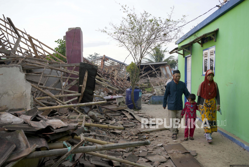 Orang-orang berjalan melewati reruntuhan rumah yang rusak akibat gempa Senin di Cianjur, Jawa Barat, Indonesia Selasa, 22 November 2022. Gempa tersebut telah merobohkan bangunan di pulau utama berpenduduk padat di Indonesia, menewaskan sejumlah orang dan melukai ratusan lainnya.