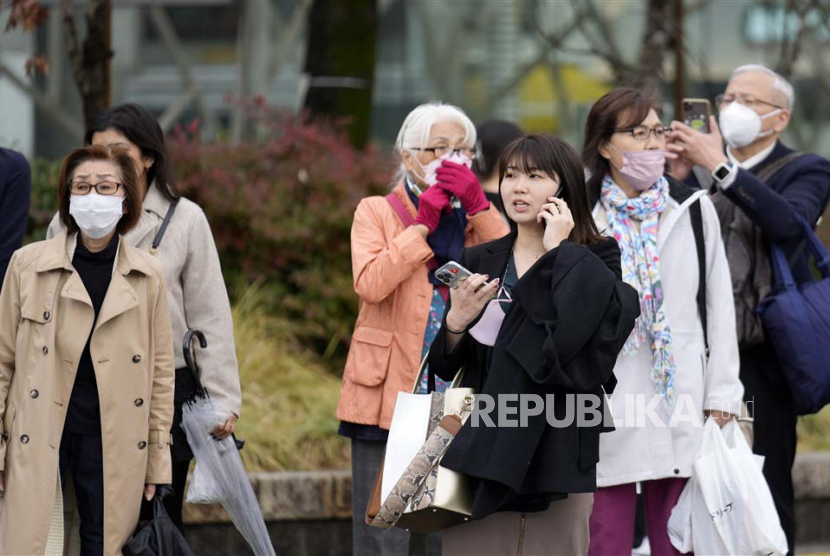  Orang-orang yang memakai masker berdiri di persimpangan di Tokyo, Jepang, 13 Maret 2023. Jepang secara resmi pada Kamis (27/4/2023) memutuskan untuk menurunkan status virus corona ke tingkat yang setara dengan flu musiman pada 8 Mei. 