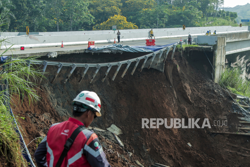 Petugas melintas di sekitar jalan tol yang amblas di ruas tol Bocimi KM 64, Sukabumi, Jawa Barat, Kamis (4/4/2024). Jalan tol Bocimi KM 64 yang amblas pada Rabu (3/4) malam tersebut mengakibatkan satu mobil dan dua orang terperosok dan arus lalu lintas dari Jakarta menuju Sukabumi dialihkan ke pintu keluar tol Cigombong. 