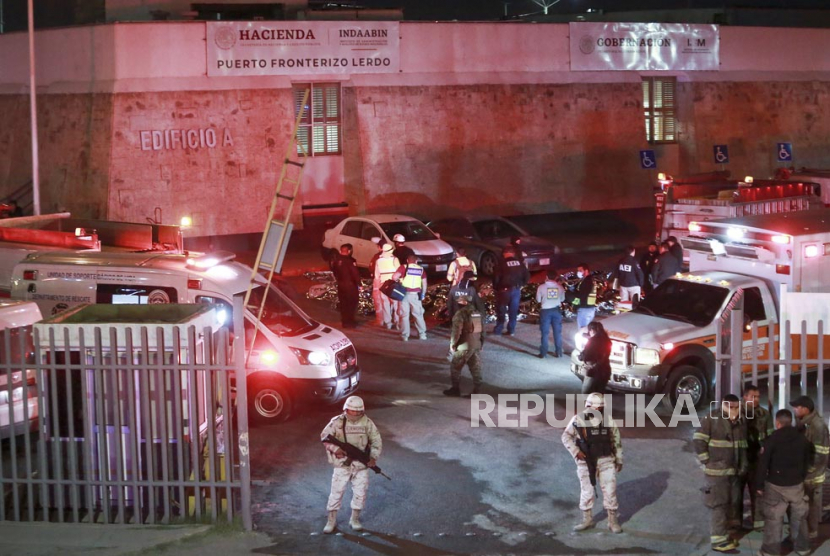 Paramedis dan aparat keamanan bekerja di tengah tubuh para migran yang tewas dalam kebakaran di pusat penahanan imigrasi di Ciudad Juarez, Meksiko, Selasa (28/3/2023).