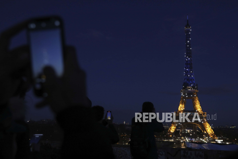 Orang-orang memotret Menara Eiffel, Jumat, 25 Februari 2022 di Paris.